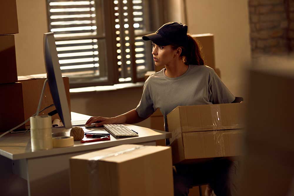 young-delivery-woman-using-desktop-pc-while-workin-2024-12-13-16-42-58-utc.jpg