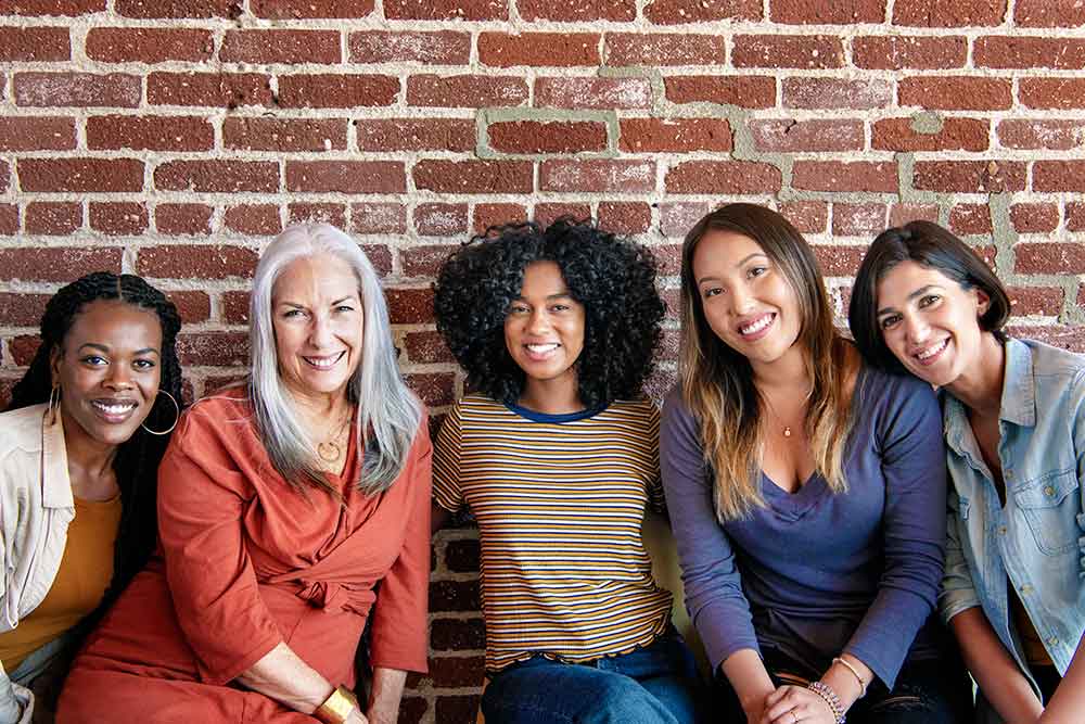 diverse-women-sitting-together-by-a-brick-wall-2023-11-27-05-23-59-utc.jpg