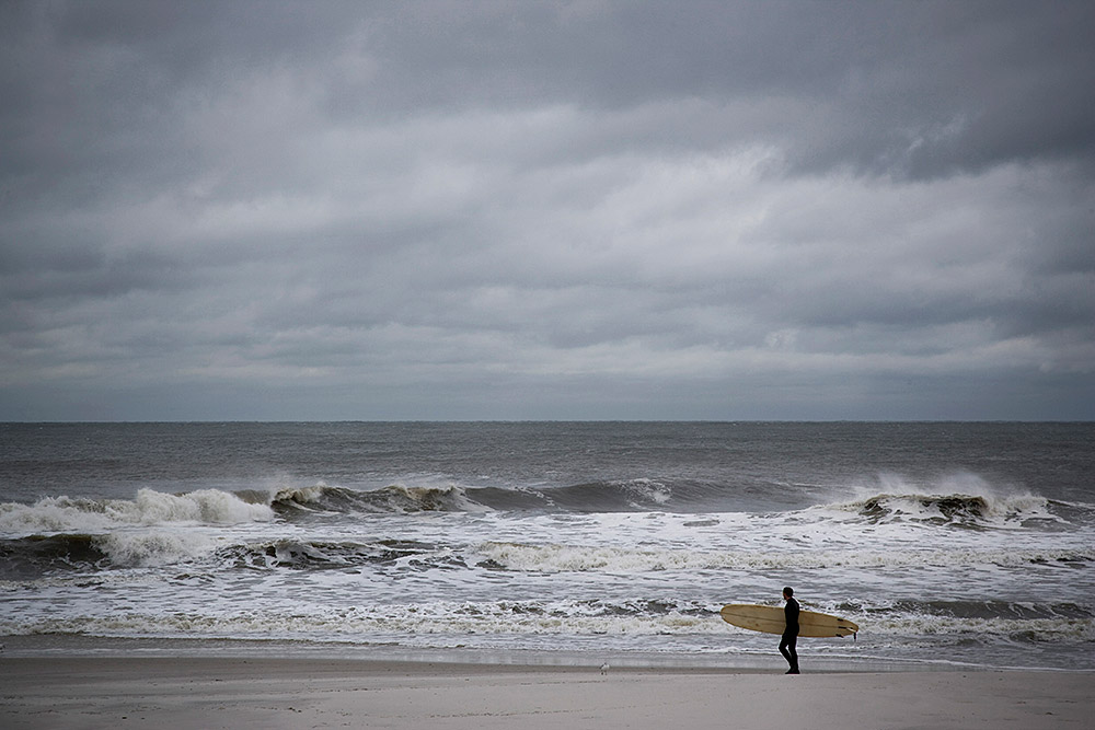 male-surfer-strolling-along-long-beach-new-york-2025-04-03-21-16-16-utc.jpg