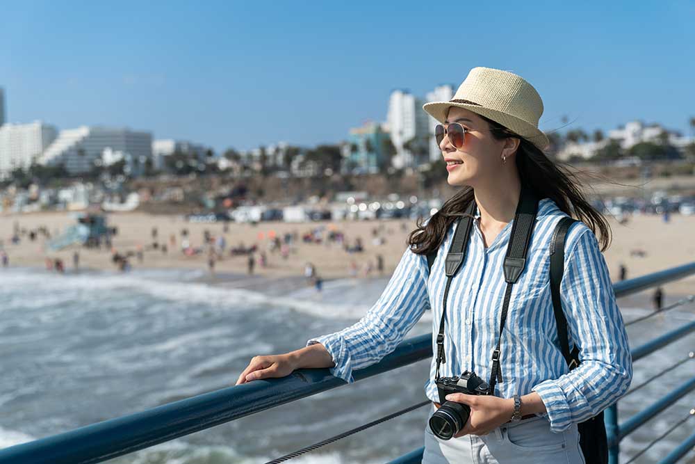 woman-with-camera-looking-over-railing-at-beach-2025-01-09-04-24-24-utc.jpg