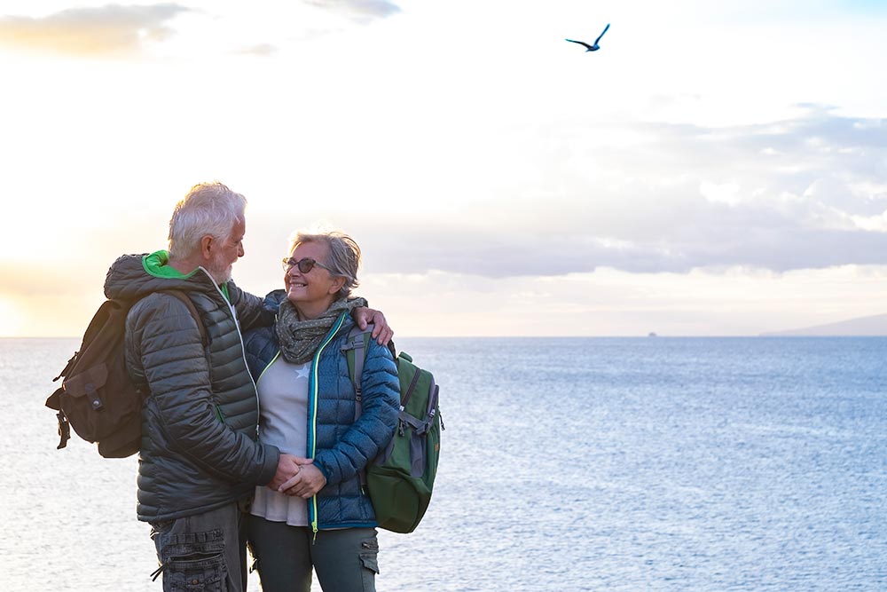smiling-senior-couple-with-backpack-on-their-back-2024-11-02-22-48-44-utc.jpg